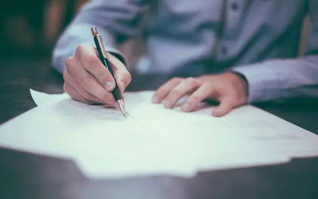 Persona firmando un escrito: abogado para querella criminal